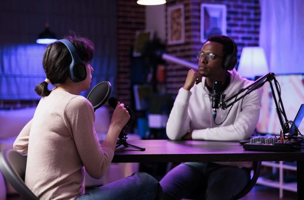 A man and woman are having a conversation during a podcast recording.